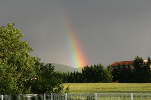 a rainbow in the sky over a field with a fence at Hôtel Valery in Montélier