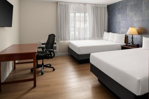 a hotel room with two beds and a desk at Granada Hotel Santa Clara in Santa Clara