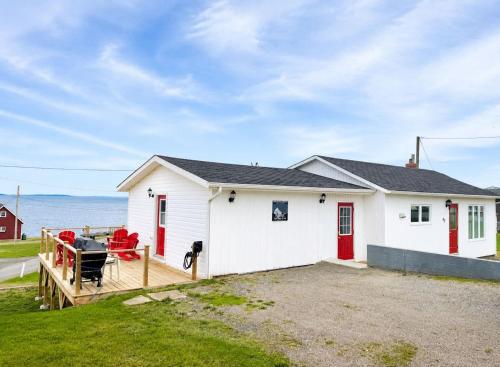 a white house with red doors and a yard at Long Beach Lookout Vacation Rental in Twillingate