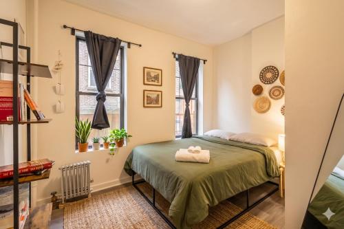 a bedroom with a green bed and two windows at The Ultimate NYC Base 1BR near Times Sq & Columbus Circle in New York