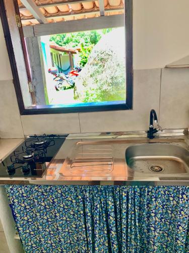 a kitchen counter with a sink and a window at Chalés Bambá in Ilhabela