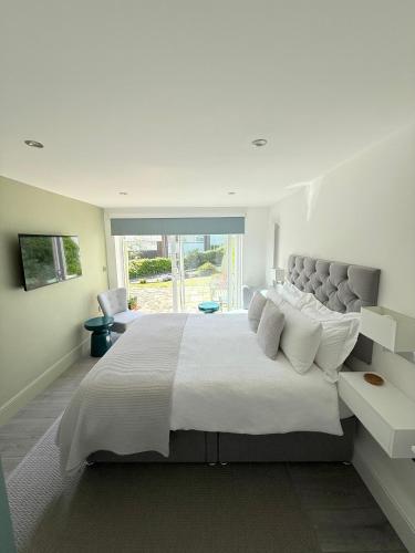 a white bedroom with a large bed with white pillows at Tŷ Treflan in Aberdyfi