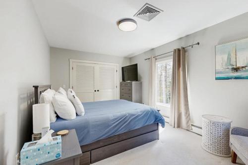a bedroom with a blue bed and a window at Tideview Estate in Cumberland Foreside