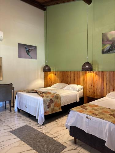 a hotel room with two beds and a table at Pousada Pitauá in Socorro