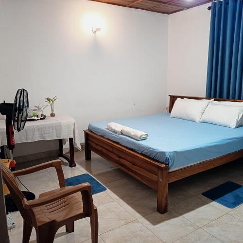 a bedroom with a bed and a chair and a table at Pavani Villa Kandy in Peradeniya
