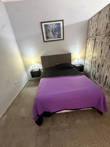 a bedroom with a large bed with a purple blanket at challet1 in Yerba Buena
