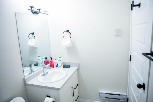 a white bathroom with a sink and a mirror at Restful Basement Suite Hideaway in Saskatoon