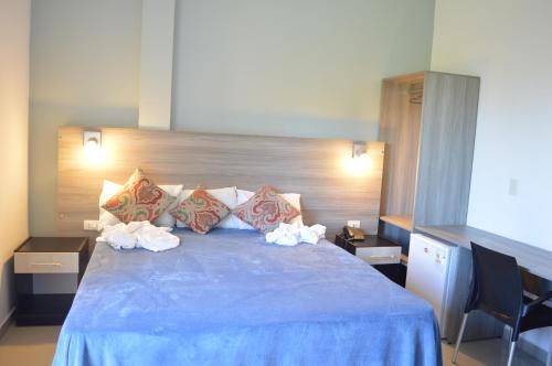 a bedroom with a blue bed with pillows at Hotel Puesta del Sol by Nobile in Encarnación