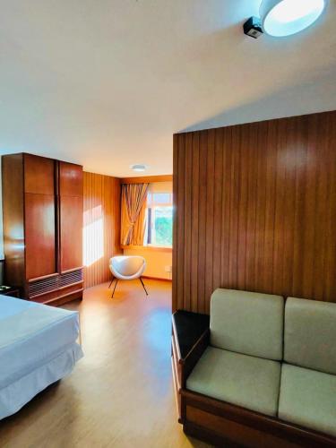 a bedroom with a bed and a couch and a chair at Lira Hotel in Curitiba