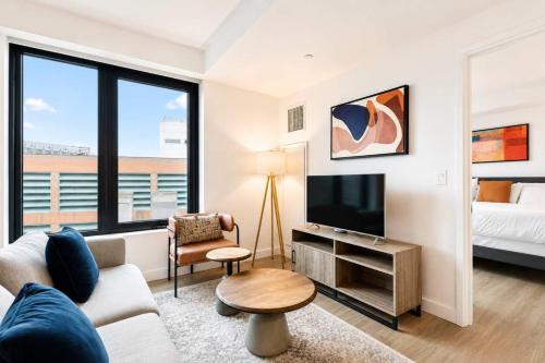 a living room with a couch and a tv and a bed at Luxury Seaport Stay Rooftop & Pool in Boston