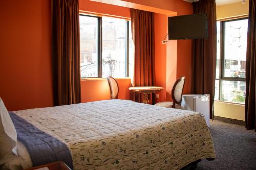 ein Hotelzimmer mit einem Bett und zwei Fenstern in der Unterkunft Hotel Sucali in Huaraz