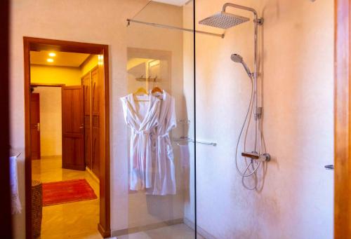 a bathroom with a shower and a robe hanging on a wall at Mila Dyafa in Oulad Akkou