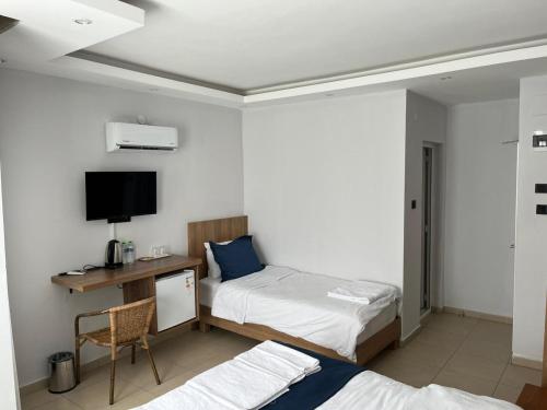 a bedroom with two beds and a desk with a tv at Caretta Vita Bella in Silifke
