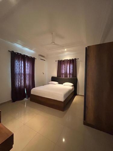 a bedroom with a bed and two windows at Fawis Lodge in Brusubi