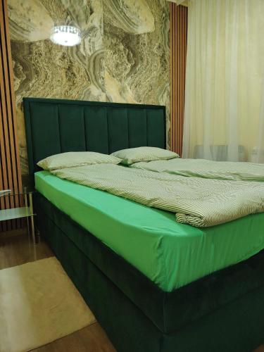 a green bed in a room with a wall at PANDORA BULEVAR Cacak in Čačak