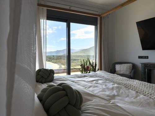 a bedroom with a white bed with a large window at Astraea Villa in Karistos