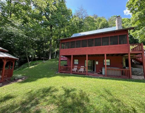 a large red house with a porch and a yard at Bigfoots River Retreat in Mineral Bluff