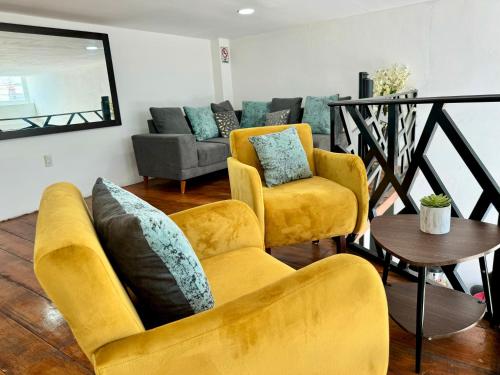 a living room with yellow chairs and a couch at Hotel DORADO in Tapachula