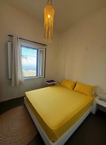 a bedroom with a yellow bed and a window at Vista Tinos in Triandáros