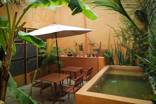a patio with a table and an umbrella and a swimming pool at Kuka y Letras in Mérida