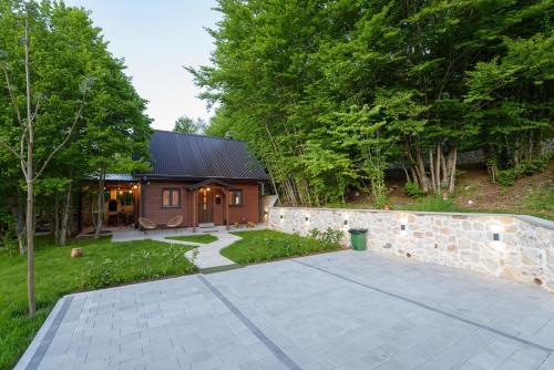 a house with a stone wall and a driveway at Mountain harmony Lovćen in Cetinje