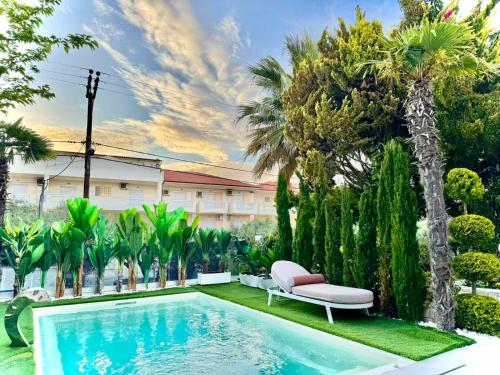 a swimming pool with a chair and palm trees at villa MEDITERAN in Pefkochori