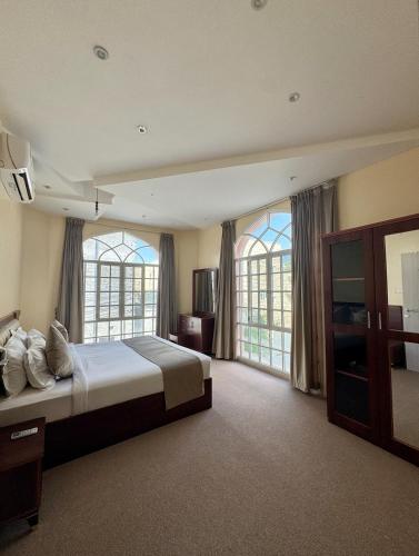 a large bedroom with a large bed and windows at Deluxe Apartment in Muscat