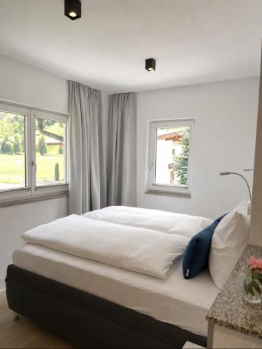 a bedroom with a large bed with two windows at ONO Apartments in Längenfeld