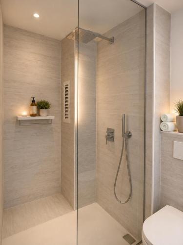 a shower with a glass door in a bathroom at A 2 passi dal mare! in Es Pujols