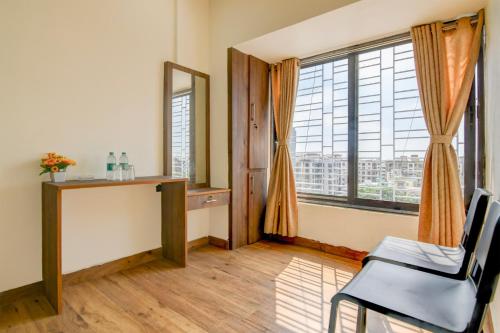 a room with a desk and a large window at Hotel O B&B Guest House in kolkata
