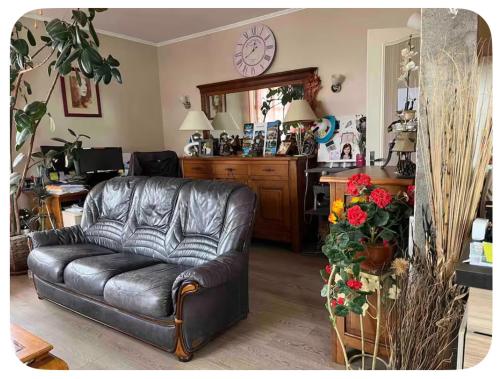 a living room with a leather couch and a kitchen at Chambre à deux pas de Beauval in Montrichard