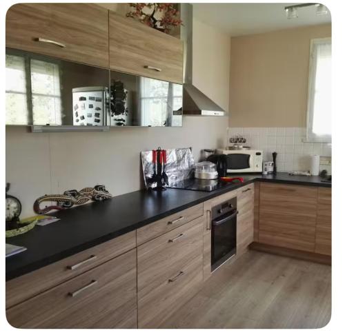 a kitchen with wooden cabinets and a black counter top at Chambre à deux pas de Beauval in Montrichard