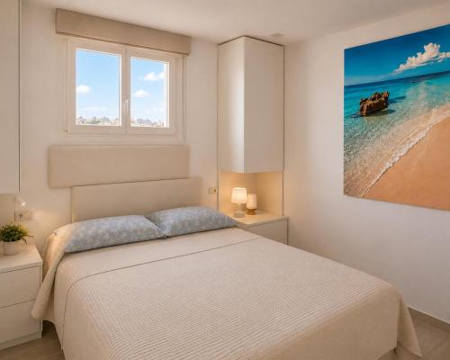 a white bedroom with a bed and a window at A 2 passi dal mare! in Es Pujols