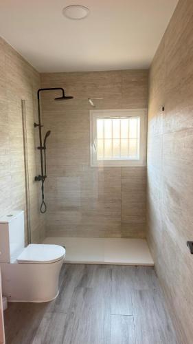 a bathroom with a toilet and a shower with a window at El Chalecito De Alicante in El Campello
