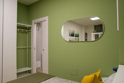a bedroom with a green wall with a mirror at Open Space Romagna 12 in San Benedetto del Tronto