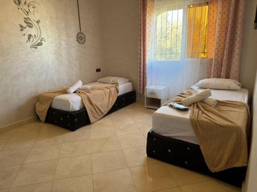 three beds in a room with a window at villa agadir in Glalcha