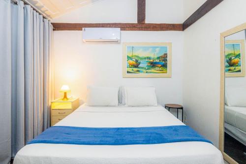a bedroom with a white bed with a blue blanket at Pousada Ilha Branca Centro in Búzios
