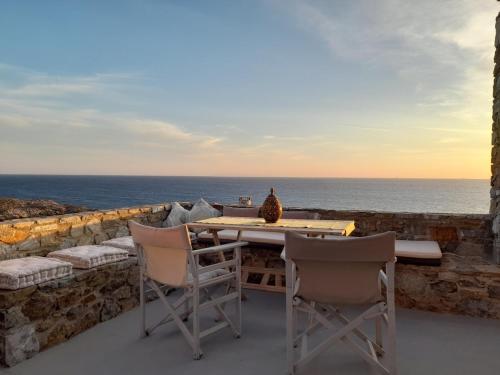 a table and chairs on a patio overlooking the ocean at il mare stone house with Aegean view in Agios Dimitrios