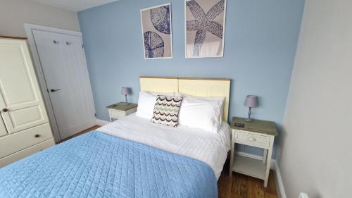 a blue bedroom with a bed and two night stands at 3 The Burrows in Braunton