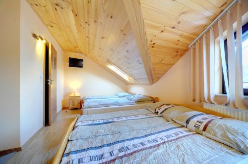 two beds in a room with a wooden ceiling at Noclegi Pod Orlikiem CENTRUM in Ustrzyki Dolne