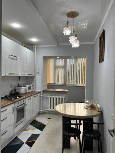 a kitchen with white cabinets and a table in it at Downtown Homestay in Bishkek