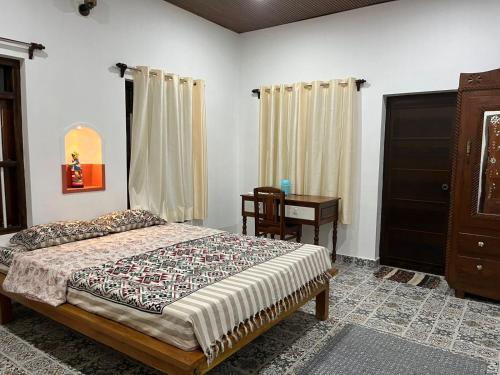 a bedroom with a bed and a dresser and a desk at Writer's Inn in Vaikom