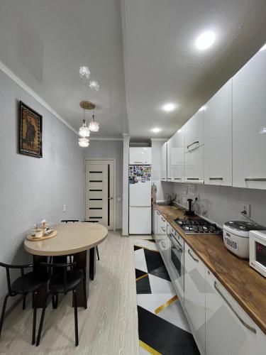 a kitchen with white cabinets and a table in it at Downtown Homestay in Bishkek