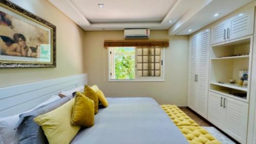 a bedroom with a bed with yellow pillows and a window at Hotel dos Príncipes - Guarujá in Guarujá