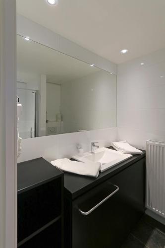 a bathroom with a sink and a large mirror at Vayamundo Oostende in Ostend