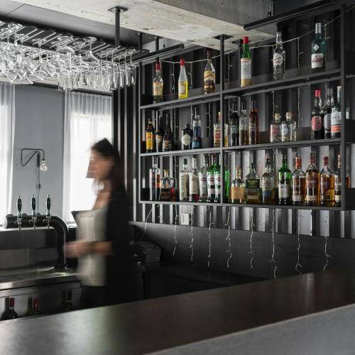 Eine Frau steht an einer Bar vor einem Regal mit Alkohol. in der Unterkunft Skuggi Hotel by Keahotels in Reykjavík
