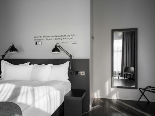 ein Schlafzimmer mit einem Bett, einem Spiegel und einem Stuhl in der Unterkunft Skuggi Hotel by Keahotels in Reykjavík