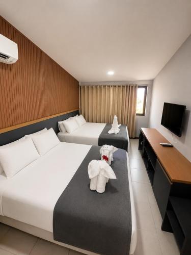 a hotel room with two beds and a teddy bear at Nannai Beira Mar, Flat Duplex em Muro Alto - Porto de Galinhas in Porto De Galinhas
