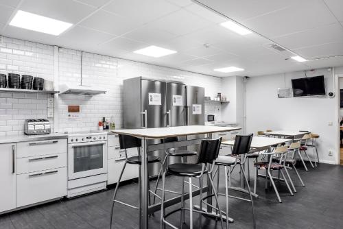 a kitchen with a refrigerator, stove, microwave and a table at City Hostel in Stockholm