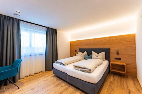 a bedroom with a large bed and a blue chair at AurAlpin Apartments in Cadipietra